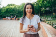 © Westend61 - Cheerful young woman holding soft drink cup while standing in park