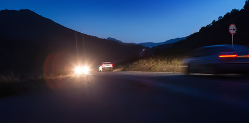 Canvas Print - Cars move on a night road in the mountains.