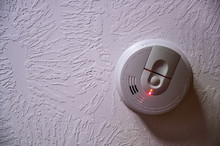 Red Light Batter Indicator On A Smoke Detector Mounted On A Ceiling
