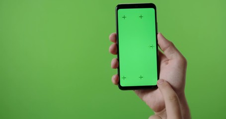 hands of man holding a phone with vertical green chroma key screen. isolated on green background, sw