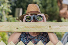 Curious Neighbor Stands Behind A Fence And Watches With Binoculars
