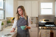 © SuperStock - Young woman in her kitchen while eating breakfast getting on her iPad