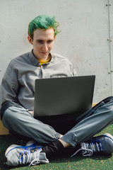 young guy works on a laptop on the street in the city space. it programmer types a programming langu