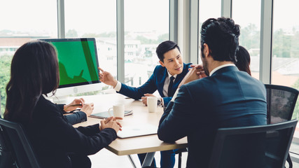 Wall Mural - Business people in the conference room with green screen chroma key TV or computer on the office table. Diverse group of businessman and businesswoman in meeting on video conference call .