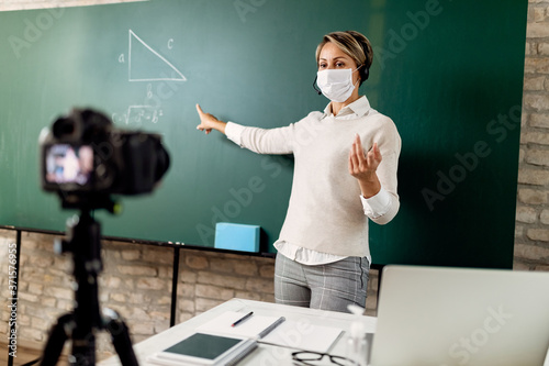 Fotografía Female teacher with a face mask giving online math lecture during coronavirus epidemic