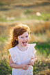 Happy child in summer. Beautiful redhead girl in white dress outdoor. Closeup portrait