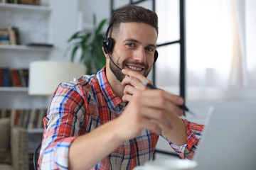 Wall Mural - Smiling young business man having video call at home office.