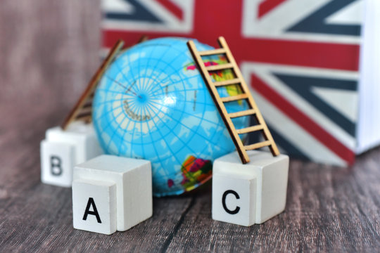 English wooden alphabet block with world globe and English book flag symbol background. English is  the language of science, aviation, computers, diplomacy, and tourism.