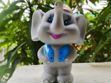 A Toy Elephant Wearing A Blue Coat And A Hat With Long Trunk And A Smiling Face.