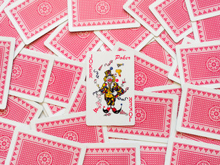 Top view of a wild card from a deck of playing cards on a pile of scattered cards with a red back. The concept of games, gambling, fun, win, loss, free time.