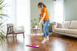 Young housewife cleaning wooden parquet using microfiber mop pad