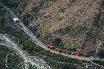 Red train going through the mountain landscape of Chimborazo province, Ecuador