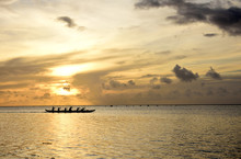 A Team Of Outrigger Canoe Paddlers At Sunset On The Peaceful Waters Of Tumon Bay, Guam, Micronesia