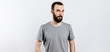 © Daria Lukoiko - A handsome brutal brunette man with a beard in a gray shirt looks seriously at the camera. Place for advertising on a gray background.
