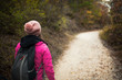 © Nikola Spasenoski - Hiker girl walking on a path in the mountains. Back view of backpacker with pink jacket in a forest. Healthy fitness lifestyle outdoors.