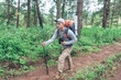 © AungMyo - Young man using hiking with backpack walking on a forest path