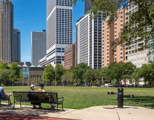 Wall Mural - senior couple sitting on bench in Chicago park with view of highrise  buildings