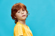 © SHOTPRIME STUDIO - red-haired child in a yellow T-shirt on a blue background