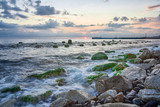 Fototapeta Pomosty - Long exposure of the coastal landscape of Imereti Adler beach with warm evening light, when the waves wash over rocks covered with seaweed