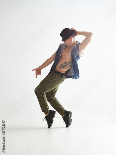 Cuadros en Lienzo Young man dancer in hat dancing moonwalk in studio isolated on white background