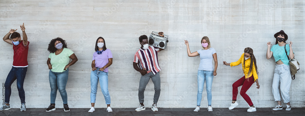 Happy friends wearing face mask listening music with vintage boombox outdoor - Multiracial young people having fun dancing together during corona virus outbreak - Youth millennial friendship concept - obrazy, fototapety, plakaty 