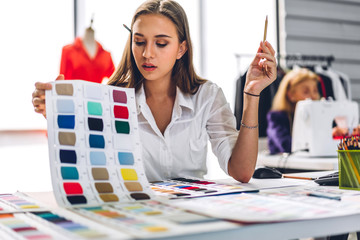 Wall Mural - Portrait of young beautiful pretty woman fashion designer stylish stand and working with color textile samples.Attractive senior woman working with mannequins and colorful fabrics at fashion studio