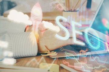 Double exposure of seo icon with man working on computer on background. Concept of search engine optimization.