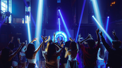 crowd of people raise hands and dancing in night club