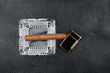 Ashtray, cigar and lighter lie on black natural leather.