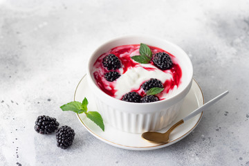 Greek yogurt with natural blackberry sauce in a white bowl. Clean eating concept. close-up. Gray background. copy space