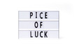 Pice of luck. Text on a vintage lightbox display placed on a white table on a light background. 