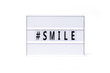 Smile. Text on a vintage lightbox display placed on a white table on a light background. 