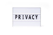 Privacy. Text on a vintage lightbox display placed on a white table on a light background. 