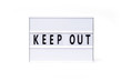 Keep Out. Text on a vintage lightbox display placed on a white table on a light background. 