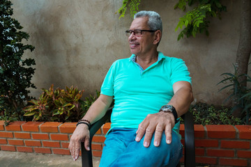 Relaxed Hispanic adult in the backyard of a house.