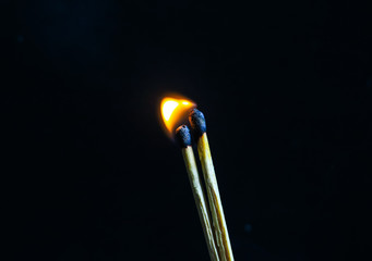 Couple of matches burning together with heat flame isolated on a black background.