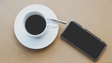 Canvas Print - Hot coffee with smartphone on wood background