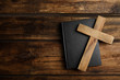 Christian cross and Bible on wooden background, top view with space for text. Religion concept