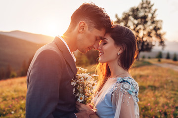 Young loving wedding couple hugging in mountains at sunset. Portrait of bride and groom in summer Carpathians.