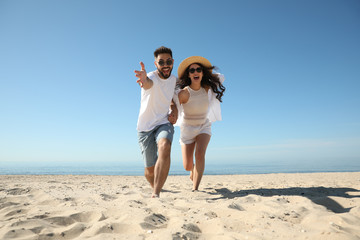 Wall Mural - Happy young couple having fun on beach near sea. Honeymoon trip