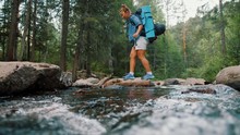 Woman Tourist With Backpack Crossing Stream In Forest, Travel Adventure Concept
