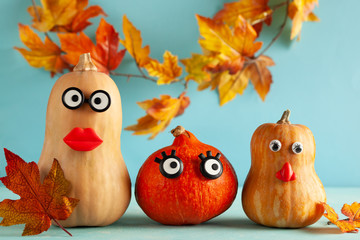 Funny pumpkins with faces on pastel blue background with copy space. Concept celebration of Halloween or Thanksgiving.