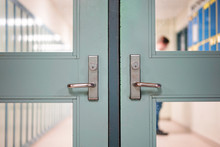 Student Returning To School. School Reopening Following Social Distancing Rule After Covid-19 Pandemic Lockdown. Door And Handle See Through Lockers And Student Standing At Background.