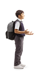 Wall Mural - Full length profile shot of a schoolboy standing, gesturing with hands and carrying a backpack