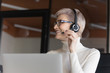 © fizkes - Happy young short haired 30s businesswoman in eyeglasses and headset with microphone consulting with colleague about decision, discussing contract or working issues with client online in office.