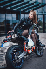 Motosport hobby. Urban custom motorcycle and his female beauty owner. Sunny streets of city.