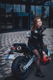 Fototapeta Miasto - A nice looking woman at the streets with her urban sport motorcycle. Motorbike sport hobby. Modern custom bike.