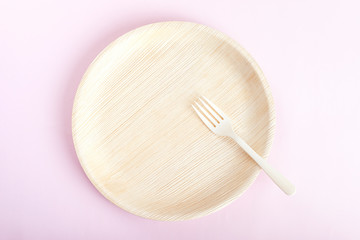 Biodegradable bamboo plate with fork on light pink background