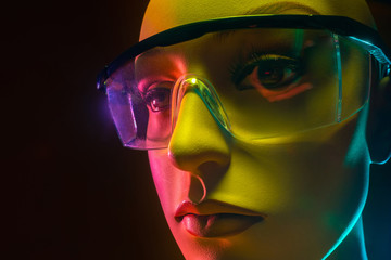 Poster - Humanoid robot. Manikin face with glasses. Woman robot face close up. Robotics. Concept - artificial intelligence. Close-up of an artificial intelligence robot head. Creation of robotics. Neon light