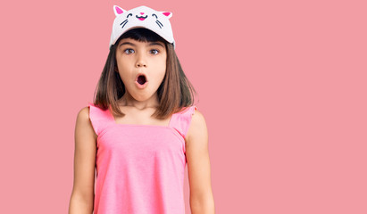 Wall Mural - Young little girl with bang wearing funny kitty cap scared and amazed with open mouth for surprise, disbelief face